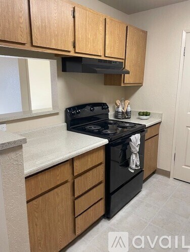 A kitchen with a black stove top oven and wooden cabinets.