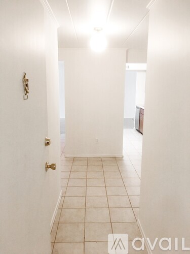 A hallway with a tiled floor and white walls.