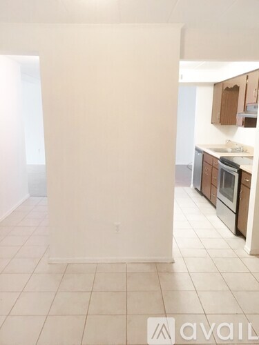A kitchen with white tiled floors and wooden cabinets.