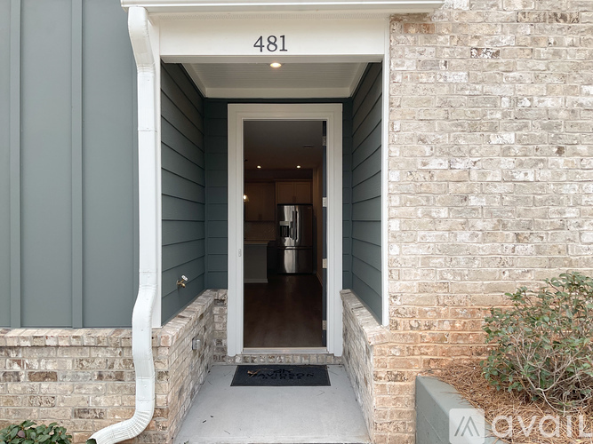 A house numbered 481 with a grey siding and a stone wall.