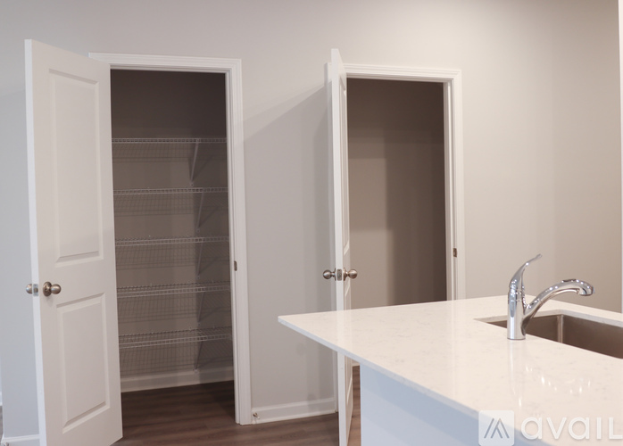 A white kitchen with a sink and two open doors.
