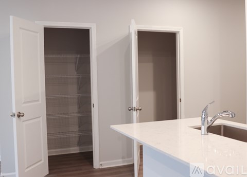 A white kitchen with a sink and two open doors.
