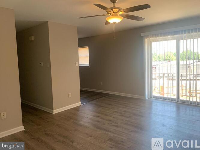 A room with a ceiling fan and sliding glass doors.