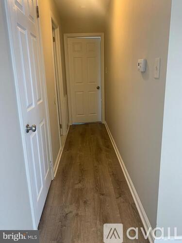 A hallway with a white door and a wooden floor.