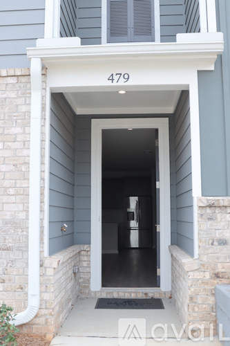 A house numbered 479 has a white door and a black mat in front of it.