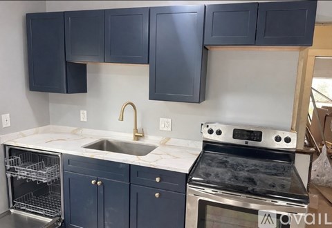 A kitchen with blue cabinets and a stainless steel oven.