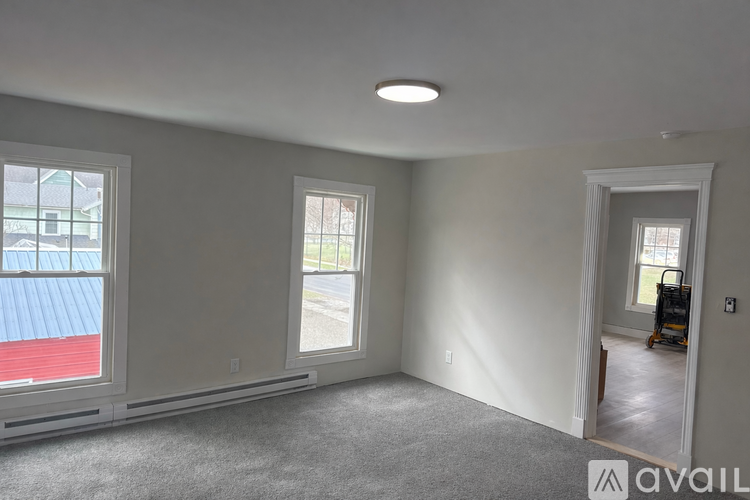 A room with a window and a door leading to a hallway.