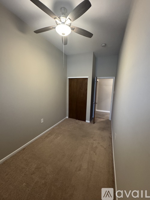 A room with a ceiling fan and carpeted floor.
