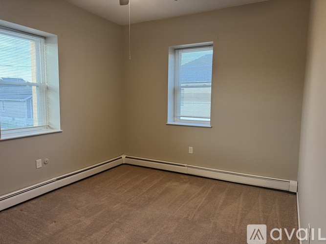 A room with a carpeted floor and two windows.