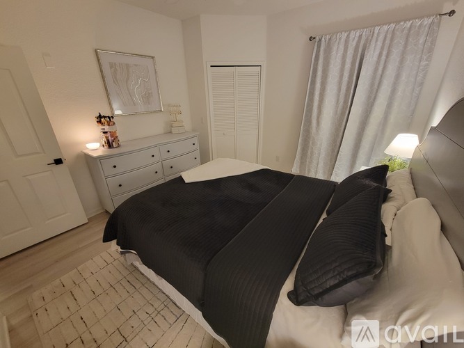 A bedroom with a large bed and a dresser with a lamp on top.