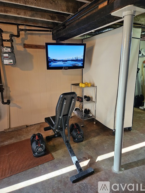 A room with a treadmill, exercise bike, and television.
