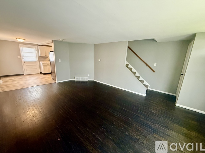 A spacious room with wooden floors and a staircase leading to another level.