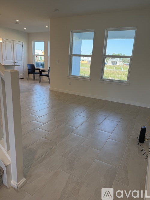A spacious room with tile flooring and two windows.