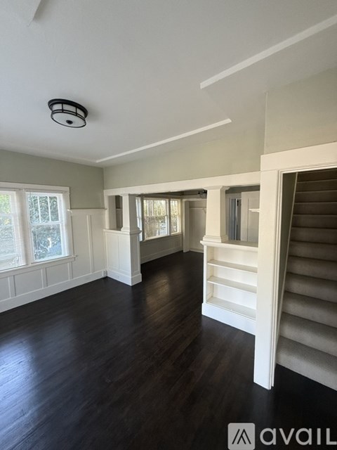 A spacious room with wooden floors and white walls.