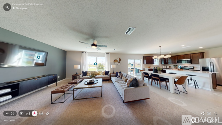 A spacious living room with a kitchen in the background.