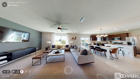 A spacious living room with a kitchen in the background.