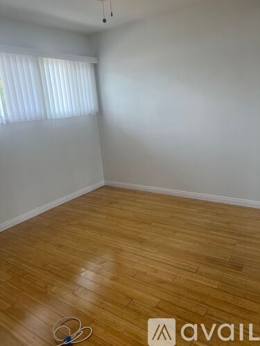 A room with wooden flooring and a window with blinds.