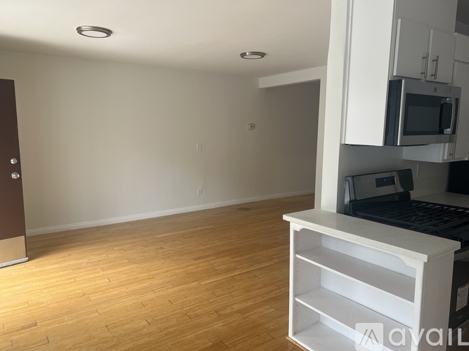 A kitchen area with a microwave, oven, and a wooden floor.