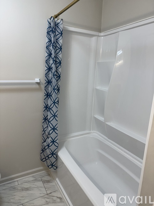 A white bathroom with a shower curtain and shelves.