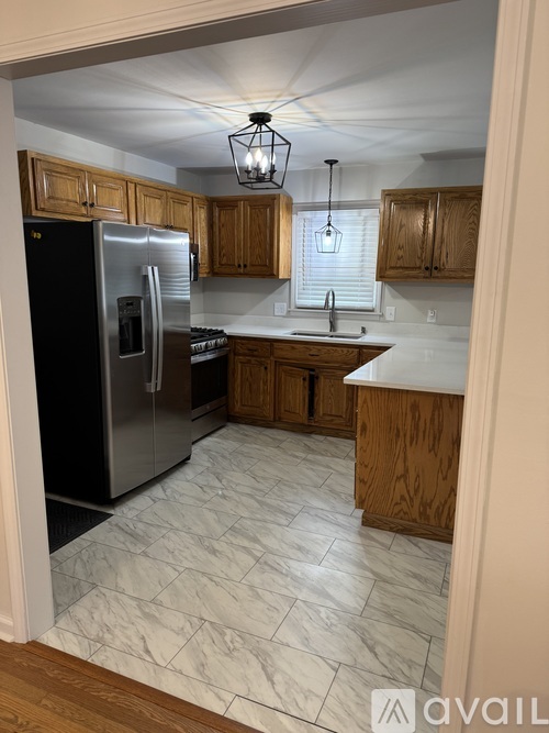 A kitchen with wooden cabinets and a marble floor.