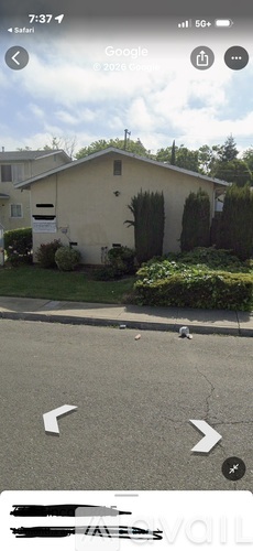 A house with a white fence and green bushes in front.