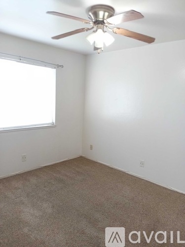 A room with a ceiling fan and carpeted floor.