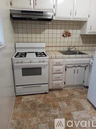 A kitchen with a white stove and white cabinets.