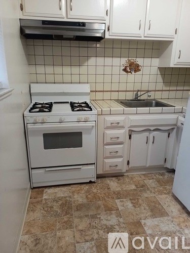 A kitchen with a white stove and white cabinets.