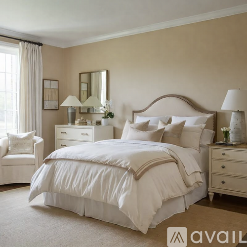 A bedroom with a large bed, a chair, and a nightstand with a lamp.