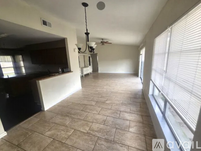 A spacious room with tiled flooring and a ceiling fan.