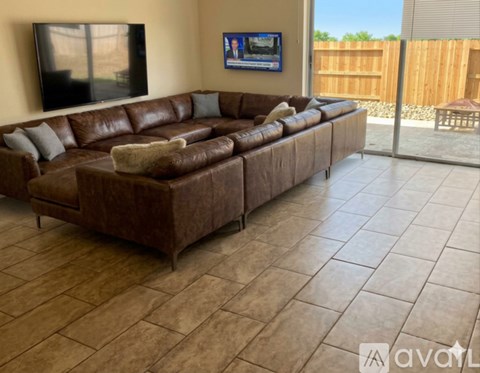 A brown leather couch with a teddy bear on it in a living room.