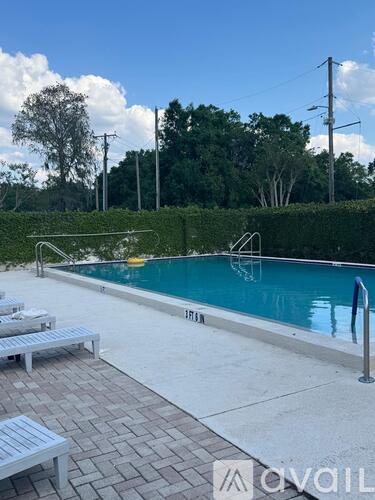 A pool with a diving board and lounge chairs.