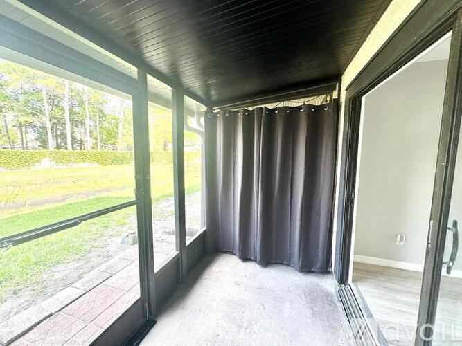 A room with a view of a grassy area through the windows.