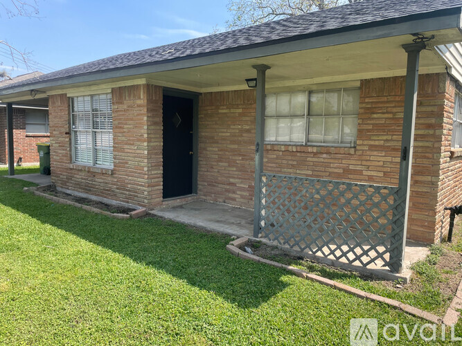 A brick house with a black door and a lattice fence.