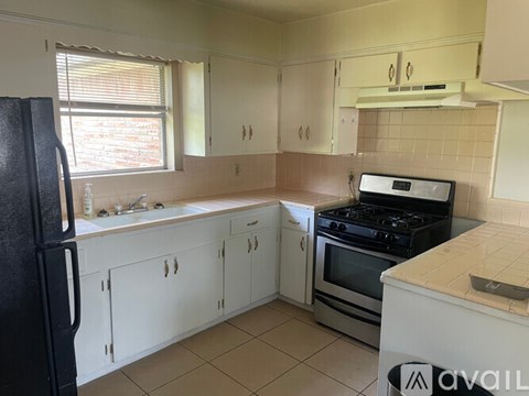 A kitchen with white cabinets and a black fridge.