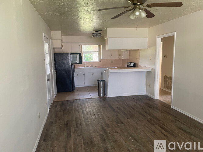 A kitchen with a refrigerator, microwave, and a ceiling fan.