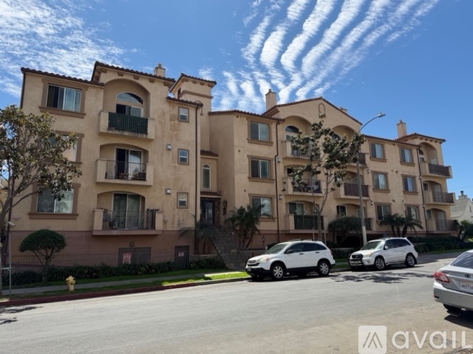 A row of beige apartment buildings with cars parked in front.
