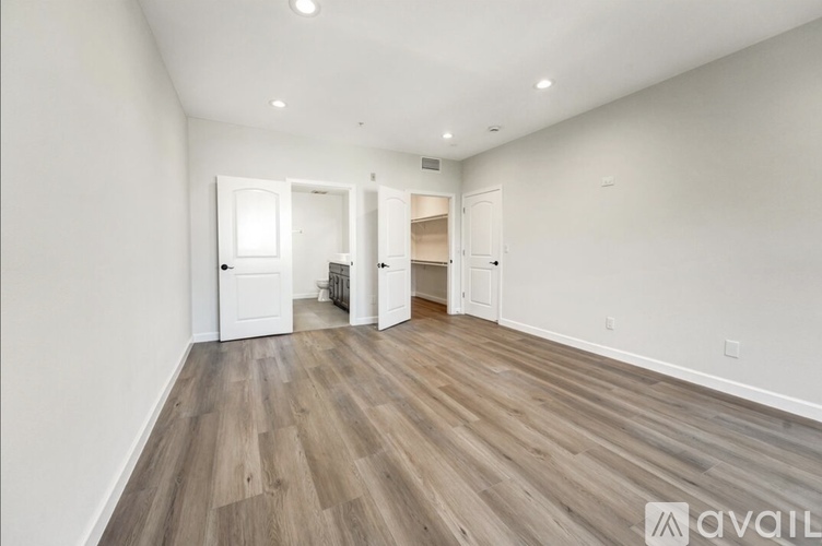A spacious room with wooden flooring and white walls.
