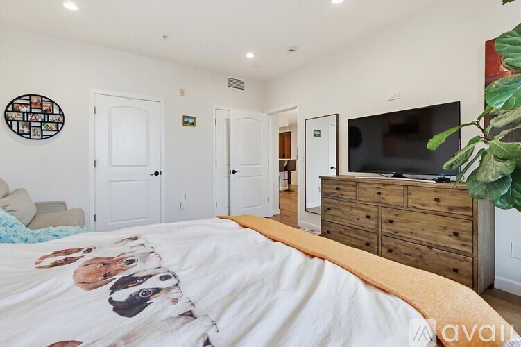 A bedroom with a bed, dresser, and a wall art of dogs.