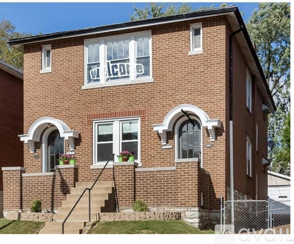 A red brick house with a white window and a sign that says "welcome".