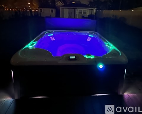 A hot tub with blue lights in the middle of a dark backyard.