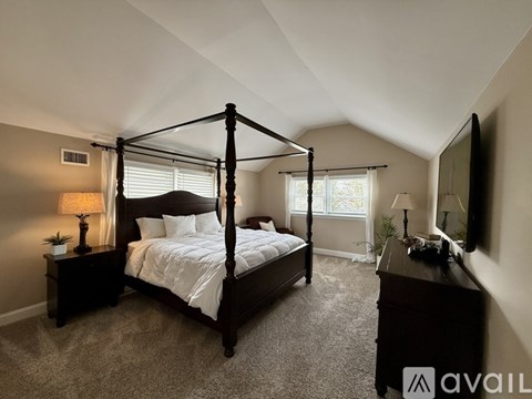 A bedroom with a four poster bed, a dresser and a television.