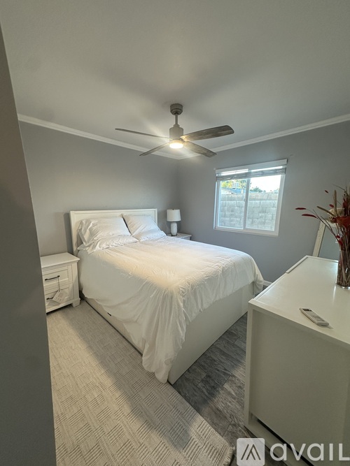 A bedroom with a bed, nightstand, and window.