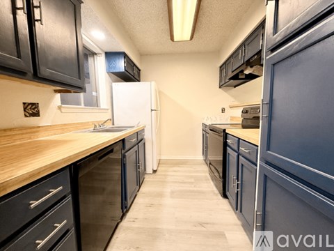 A kitchen with black cabinets and a white refrigerator.