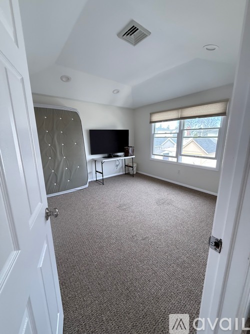 A room with a carpeted floor, a television, and a sliding glass door.