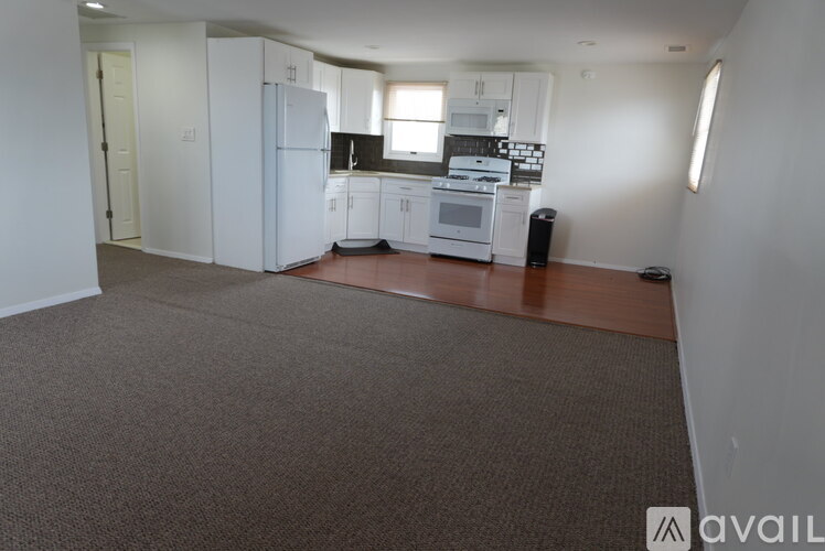 A kitchen with white appliances and a brown floor.