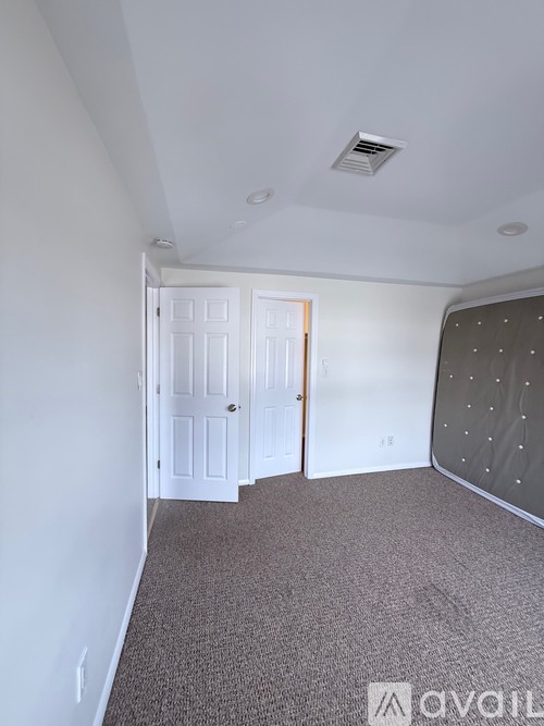 A room with a carpeted floor and a white door.