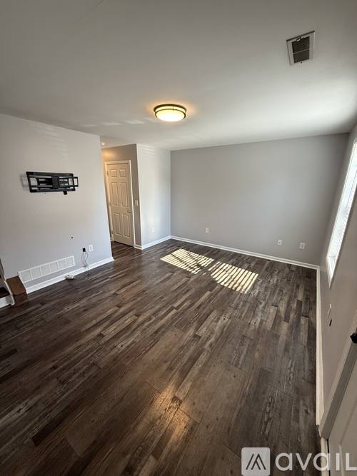 A room with wooden flooring and a flat screen TV mounted on the wall.