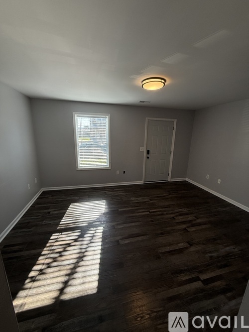 A room with wooden flooring and a window letting in sunlight.