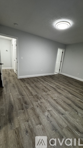 A room with wooden flooring and two doors.